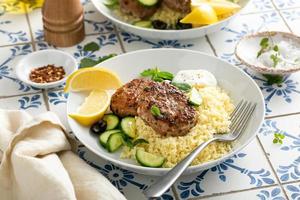 Herb turkey patties served with couscous and fresh salad