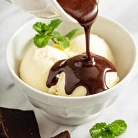 Pouring chocolate sauce on ice cream photo