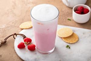 Strawberry or raspberry iced milk cocktail in a tall glass photo