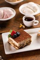 Tiramisu dessert served on a white plate with espresso photo