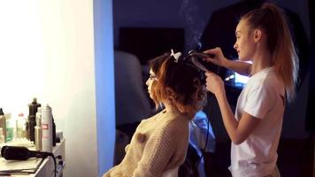 Blonde Stylistin macht einer jungen Frau im Haarstudio eine Frisur video