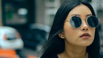 jong Aziatisch brunette in zonnebril wandelingen in de omgeving van de straat in de stad video