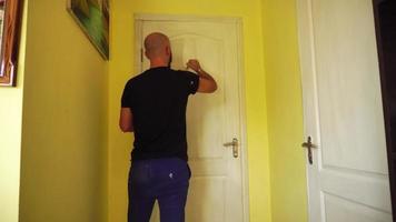 man paints the door in the room in white color with a paint brush video