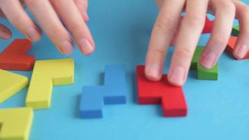 Logical thinking and finishing task concept. Woman hand folds different shapes wooden blocks to finish puzzle video