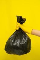 concepto más limpio, mano en guantes de goma y bolsa de plástico con residuos de basura
