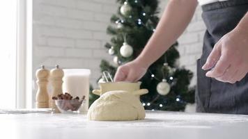 Chef cutting cinnamon rolls, christmas tree with lights on the background video