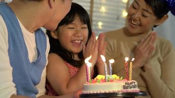 Father and mother holding cake to daughter in birthday party together. video