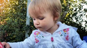Cerrar el retrato de una hermosa niñita cortando un césped en el jardín verde video