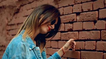 cheerful  blonde with red lips walks across a brick wall in the street video