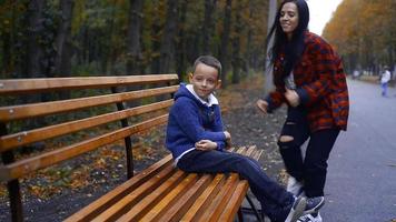 mooi brunette mam sluipen omhoog naar haar weinig zoon van achter Bij warm herfst dag video