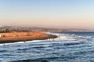 Waves in the Pacific Ocean and view of the beach at sunset, in Newport Beach, California. photo