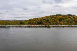Train riding up the Hudson River in New York State with a background of fall foliage. photo