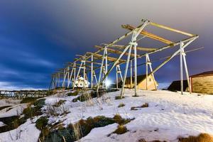 Winter in Reine, Lofoten Islands, Norway. Stocks for drying fish at night. photo