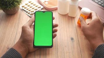 mano sostiene un teléfono inteligente con pantalla verde y contenedor de medicamentos video