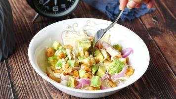 Eating avocado salad from a bowl on the table . video