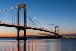 el puente bronx-whitestone reflejado en el río este por la noche en nueva york. foto