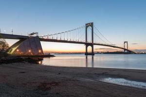 el puente bronx-whitestone reflejado en el río este por la noche en nueva york. foto