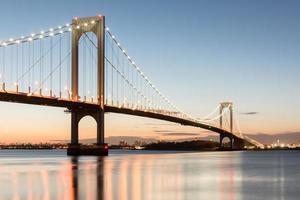 el puente bronx-whitestone reflejado en el río este por la noche en nueva york. foto