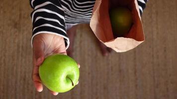 Top view of green apple and reusable shopping bag on wooden background video