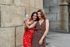 Two girls interacting with a mobile phone and taking silly selfie photos in New York City