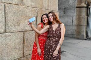 Two girls interacting with a mobile phone and taking silly selfie photos in New York City