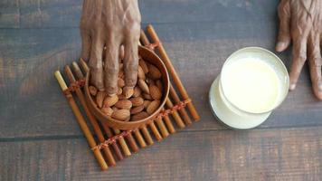 Close up of a bowl of almond nuts and milk on wooden table video