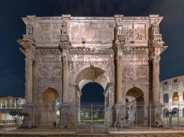 The Arch of Constantine is a triumphal arch in Rome, situated between the Colosseum and the Palatine Hill in Rome, Italy at night. photo