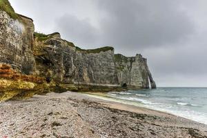 Spectacular natural cliffs Aval of Etretat and beautiful famous coastline on a cloudy day in Normandy, France, Europe. photo