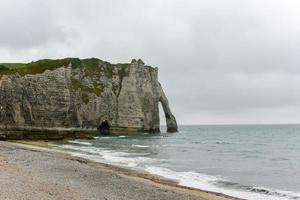 Spectacular natural cliffs Aval of Etretat and beautiful famous coastline on a cloudy day in Normandy, France, Europe. photo