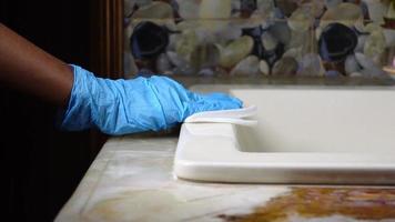 mano en guantes de goma azul limpiando una superficie plana con un pañuelo video