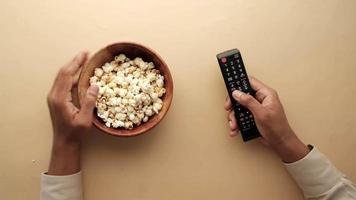 hoog hoek visie van mannen hand- plukken popcorn en gebruik makend van TV afgelegen video