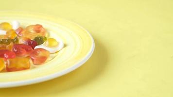 Gummy candies on a plate on yellow background video