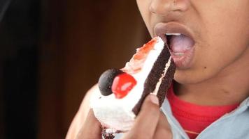 Teenage boy eating chocolate cake close up , video