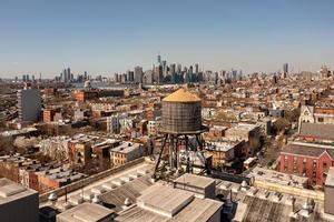 Brooklyn, New York - Apr 8, 2021 -  Water tower and a view of the Manhattan Skyline in the background. photo