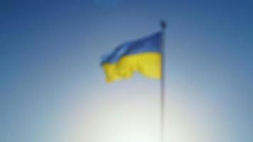 vista borrosa en cámara lenta de la bandera de ucrania ondeando en el viento contra el cielo. el símbolo nacional ucraniano del país es azul y amarillo en un asta de bandera. símbolo de estado de los ucranianos. video