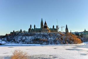 la colina del parlamento y la casa del parlamento canadiense en ottawa, canadá, al otro lado del río congelado de ottawa durante el invierno. foto