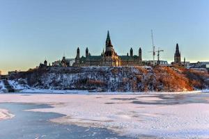 la colina del parlamento y la casa del parlamento canadiense en ottawa, canadá, al otro lado del río congelado de ottawa durante el invierno. foto