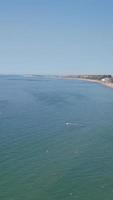 imagens aéreas da praia de areia britânica e oceano. filmagem 4k vertical e estilo retrato da praia de bournemouth com a câmera do drone durante o pôr do sol video