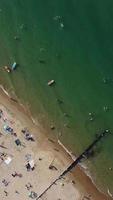 imagens aéreas da praia de areia britânica e oceano. filmagem 4k vertical e estilo retrato da praia de bournemouth com a câmera do drone durante o pôr do sol video