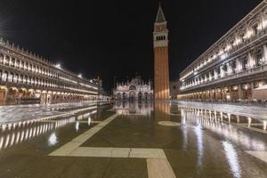 Saint Mark's Square in Venice Italy at night with reflections in the water. photo