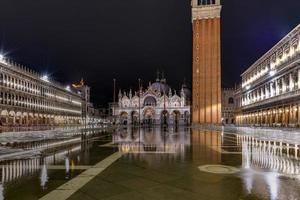 Saint Mark's Square in Venice Italy at night with reflections in the water. photo