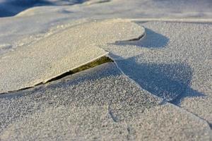 roca que se agrieta a través del hielo en vagspollen en las islas lofoten, noruega en el invierno. foto