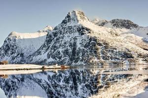 impulsado por bo con montañas reflejadas en el agua. en las islas lofoten, noruega en el invierno. foto