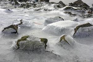 roca que se agrieta a través del hielo en vagspollen en las islas lofoten, noruega en el invierno. foto