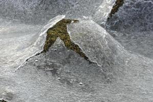 roca que se agrieta a través del hielo en vagspollen en las islas lofoten, noruega en el invierno. foto