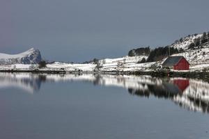 rorbuer reflejado a lo largo de vagspollen en las islas lofoten, noruega en el invierno. foto