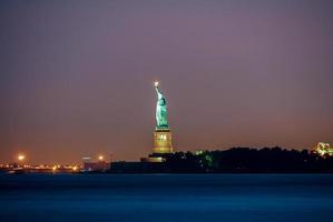 estatua de la libertad en la noche desde el parque de batería, ciudad de nueva york foto