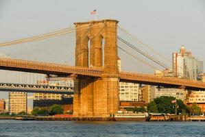 puente de brooklyn contra el horizonte de nueva york al atardecer foto