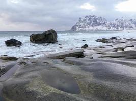 olas que fluyen sobre la playa de utakleiv, islas lofoten, noruega en el invierno. foto