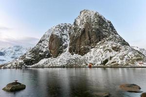 cabaña de pesca en el pico de la montaña hamnoy y lilandstinden en invierno en reine, islas lofoten, noruega. foto